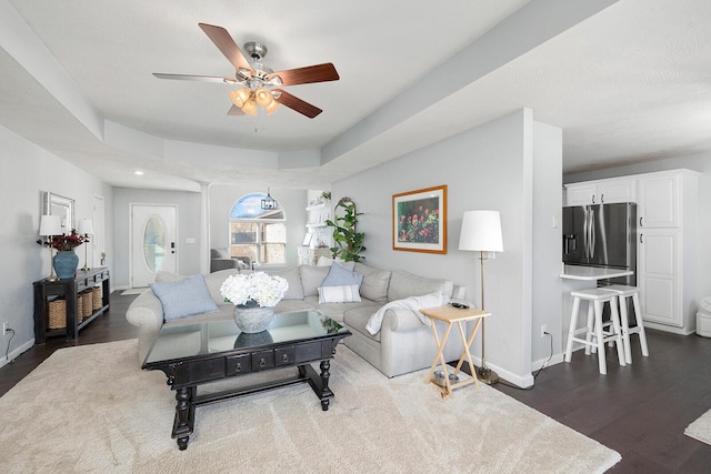 living room with ceiling fan, dark hardwood / wood-style flooring, and a raised ceiling