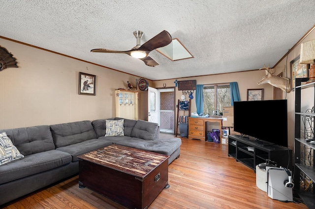 living room with ornamental molding, a textured ceiling, ceiling fan, and light wood-type flooring