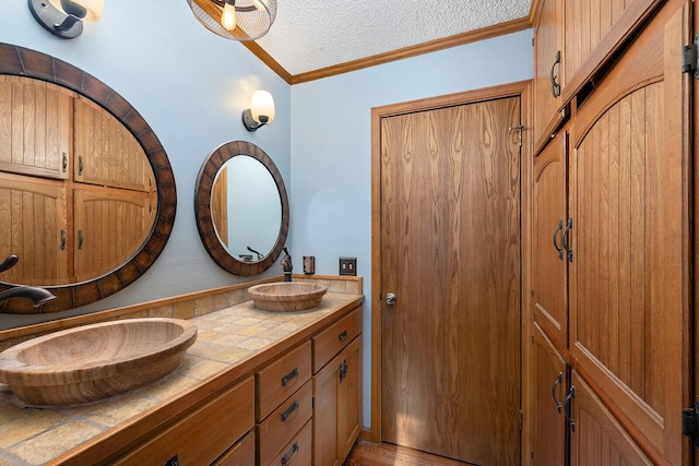 bathroom featuring ornamental molding, vanity, and a textured ceiling