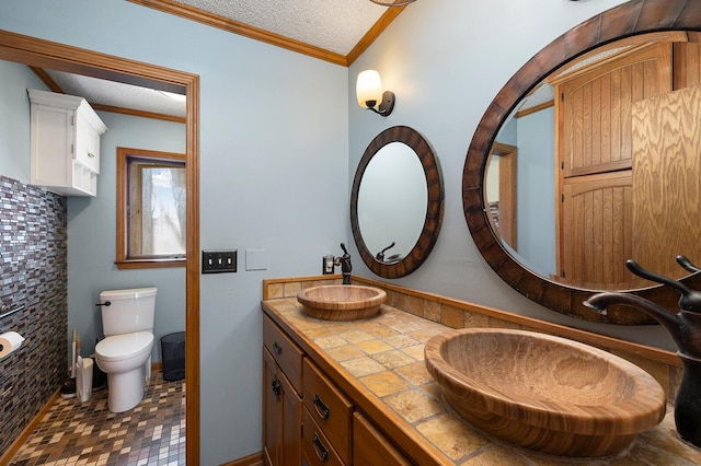 bathroom with vanity, a textured ceiling, ornamental molding, and toilet