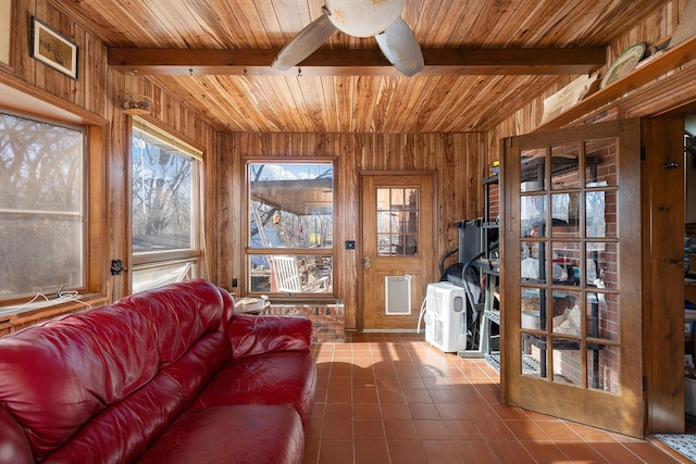 tiled living room with beam ceiling, a wealth of natural light, and wooden walls