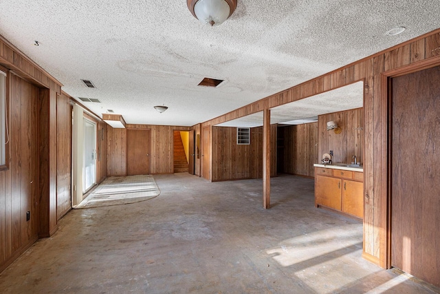 basement with a textured ceiling and wooden walls