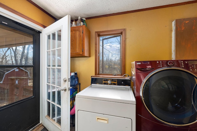 laundry room featuring cabinets, crown molding, separate washer and dryer, and a textured ceiling