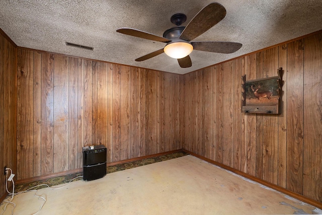 spare room with a textured ceiling and wood walls