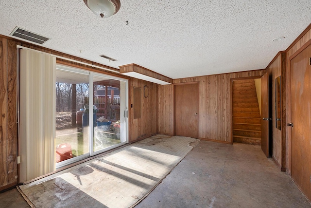 spare room featuring a textured ceiling and wooden walls