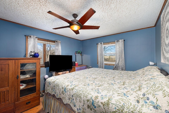 bedroom with ceiling fan, crown molding, a textured ceiling, and hardwood / wood-style flooring