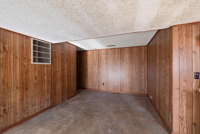 interior space with a textured ceiling and wooden walls