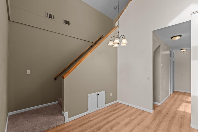 interior space featuring hardwood / wood-style flooring, a towering ceiling, and a notable chandelier