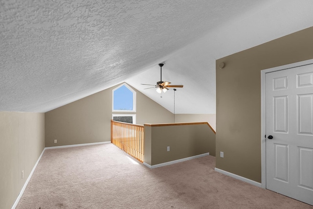 additional living space with ceiling fan, vaulted ceiling, light carpet, and a textured ceiling