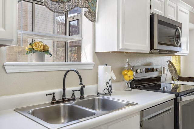 kitchen with stainless steel appliances, sink, and white cabinets