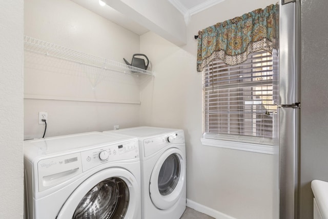 clothes washing area featuring crown molding and washer and dryer