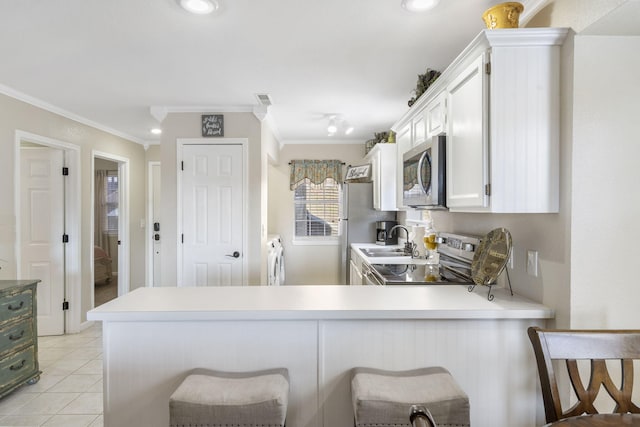 kitchen with a breakfast bar area, white cabinetry, light tile patterned floors, appliances with stainless steel finishes, and kitchen peninsula