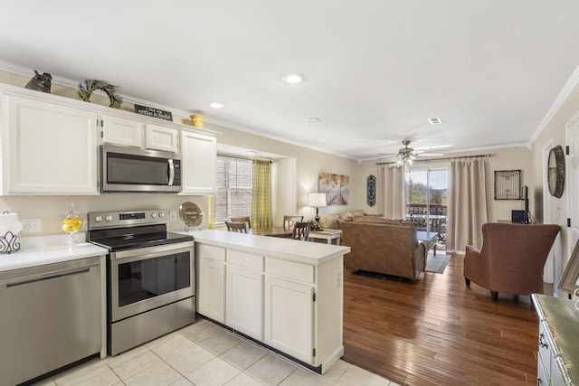 kitchen featuring white cabinetry, crown molding, stainless steel appliances, and kitchen peninsula