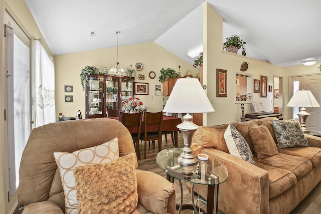 living room with hardwood / wood-style flooring, lofted ceiling, and an inviting chandelier