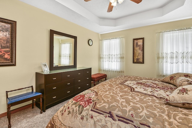 carpeted bedroom featuring a tray ceiling and ceiling fan