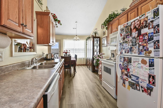 kitchen featuring pendant lighting, sink, white appliances, a textured ceiling, and light wood-type flooring