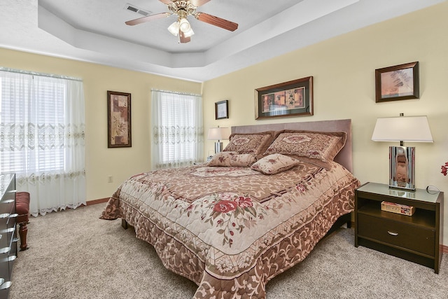 carpeted bedroom featuring ceiling fan and a tray ceiling