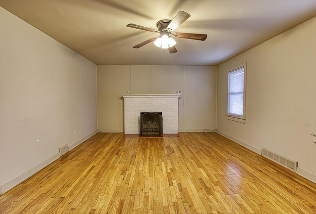 unfurnished living room with a brick fireplace, ceiling fan, and light wood-type flooring