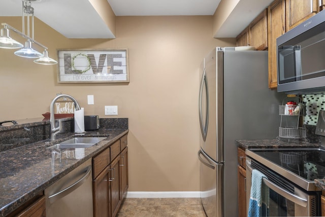 kitchen featuring sink, appliances with stainless steel finishes, pendant lighting, dark stone counters, and backsplash