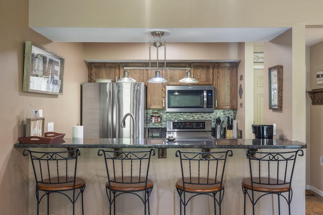 kitchen with hanging light fixtures, appliances with stainless steel finishes, a breakfast bar area, and decorative backsplash