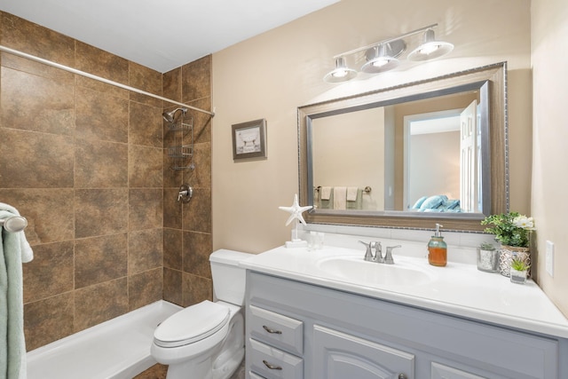 bathroom with vanity, tiled shower, and toilet