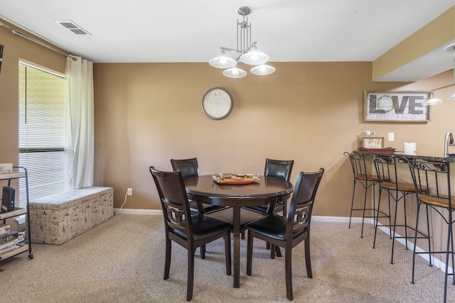 carpeted dining space featuring a chandelier