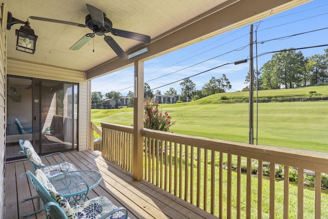 wooden terrace with a lawn and ceiling fan