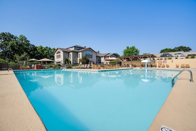 community pool with a patio area and fence