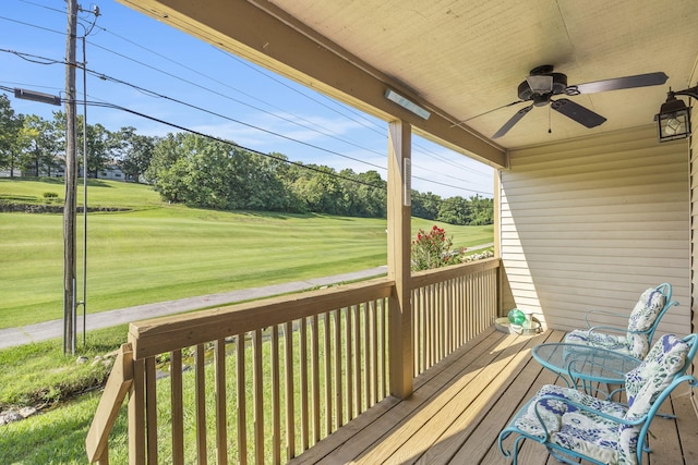 wooden deck featuring ceiling fan, covered porch, and a lawn