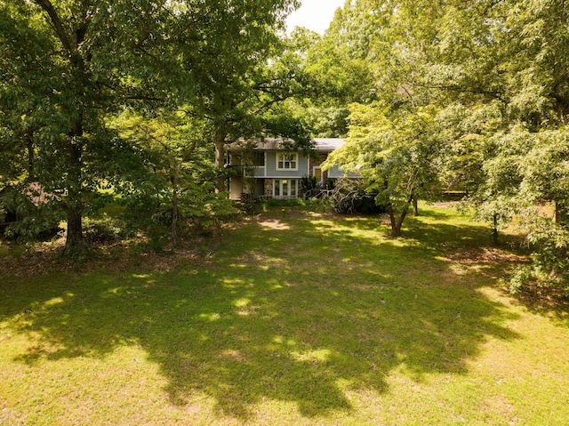view of grassy yard featuring a forest view