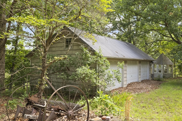 view of side of property featuring metal roof and a detached garage