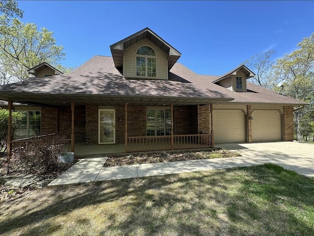 view of front of house with an attached garage, covered porch, a shingled roof, concrete driveway, and brick siding