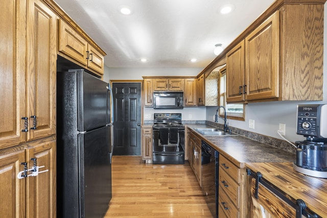 kitchen featuring wood counters, sink, light wood-type flooring, and black appliances