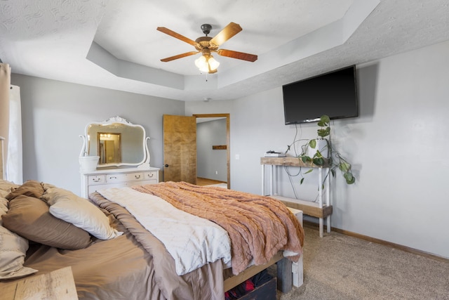 bedroom with a tray ceiling, light colored carpet, and ceiling fan