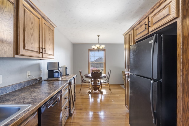 kitchen with a textured ceiling, light wood-type flooring, a notable chandelier, pendant lighting, and black appliances