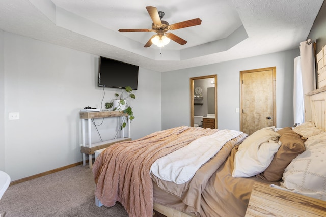 bedroom featuring ensuite bath, carpet flooring, ceiling fan, and a tray ceiling