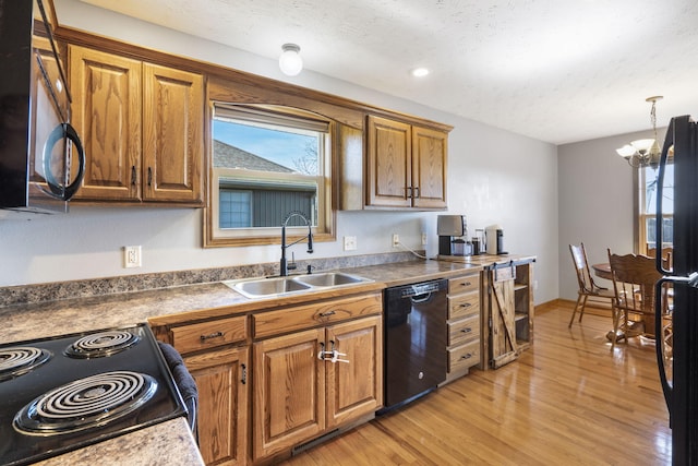 kitchen featuring pendant lighting, sink, black appliances, a textured ceiling, and light wood-type flooring