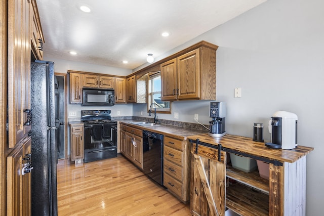 kitchen with light wood-type flooring, sink, and black appliances