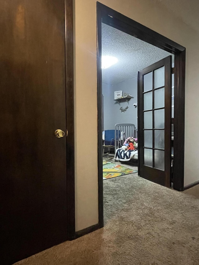 corridor with carpet floors and a textured ceiling