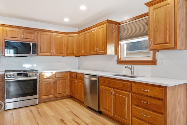 kitchen with stainless steel appliances, sink, and light hardwood / wood-style floors