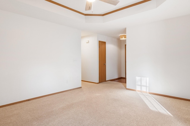 unfurnished room featuring a raised ceiling, ceiling fan, and carpet