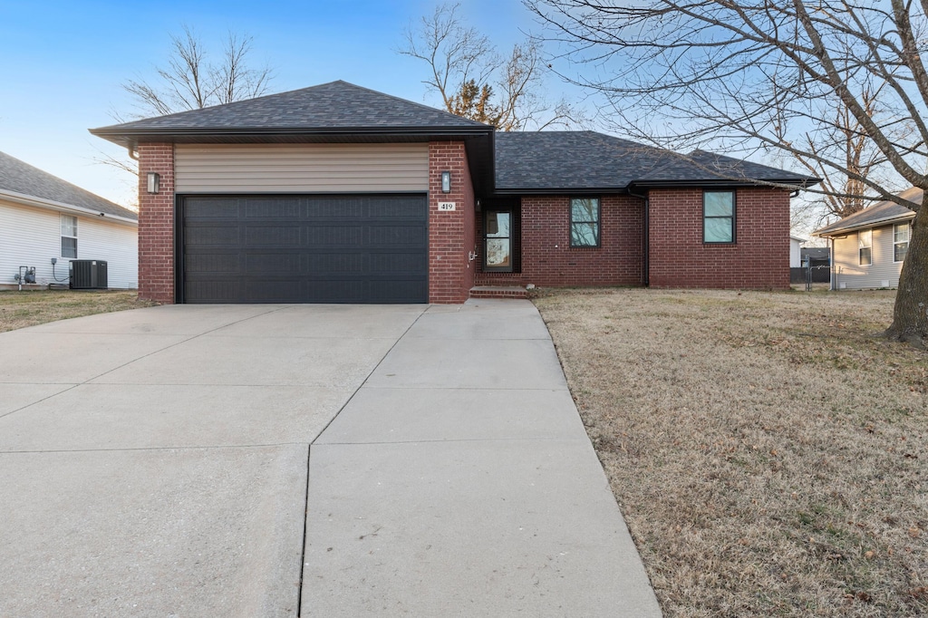 view of front of property with cooling unit, a garage, and a front yard