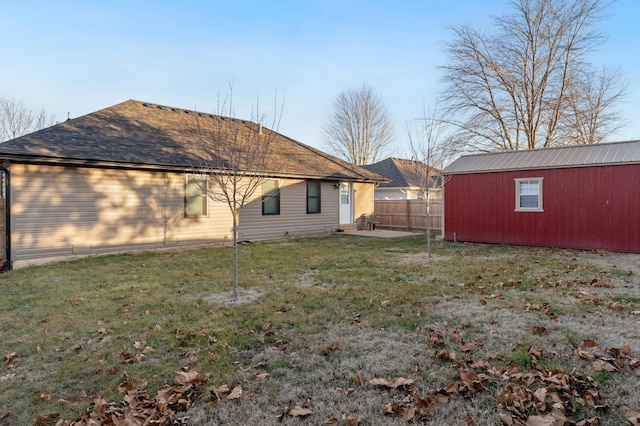 rear view of property featuring a yard and an outbuilding