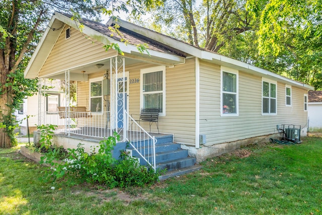 view of front facade featuring a front yard, covered porch, and cooling unit