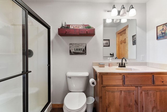 bathroom with an enclosed shower, vanity, and toilet