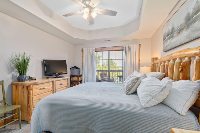 carpeted bedroom featuring a tray ceiling, access to outside, and ceiling fan