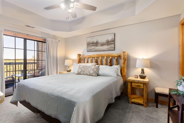 bedroom with ceiling fan, access to exterior, a raised ceiling, and carpet