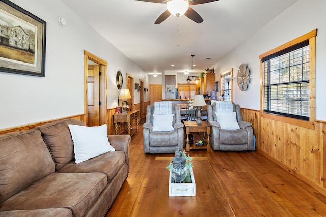 living room featuring hardwood / wood-style flooring, ceiling fan, and wood walls