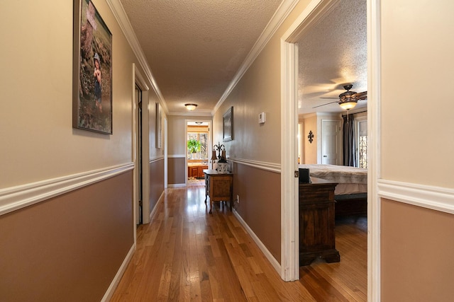 hall featuring wood-type flooring, crown molding, and a textured ceiling