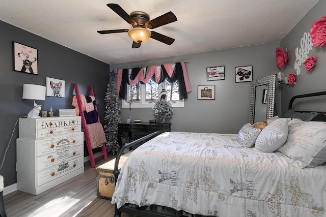 bedroom with ceiling fan, light hardwood / wood-style floors, and a textured ceiling